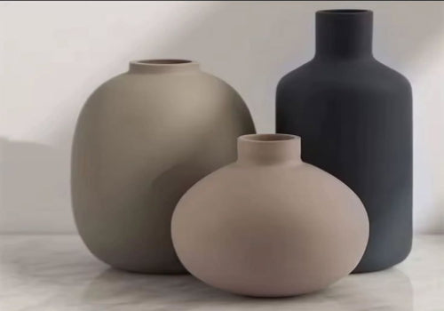 Three ceramic vases in gray and beige on a light background